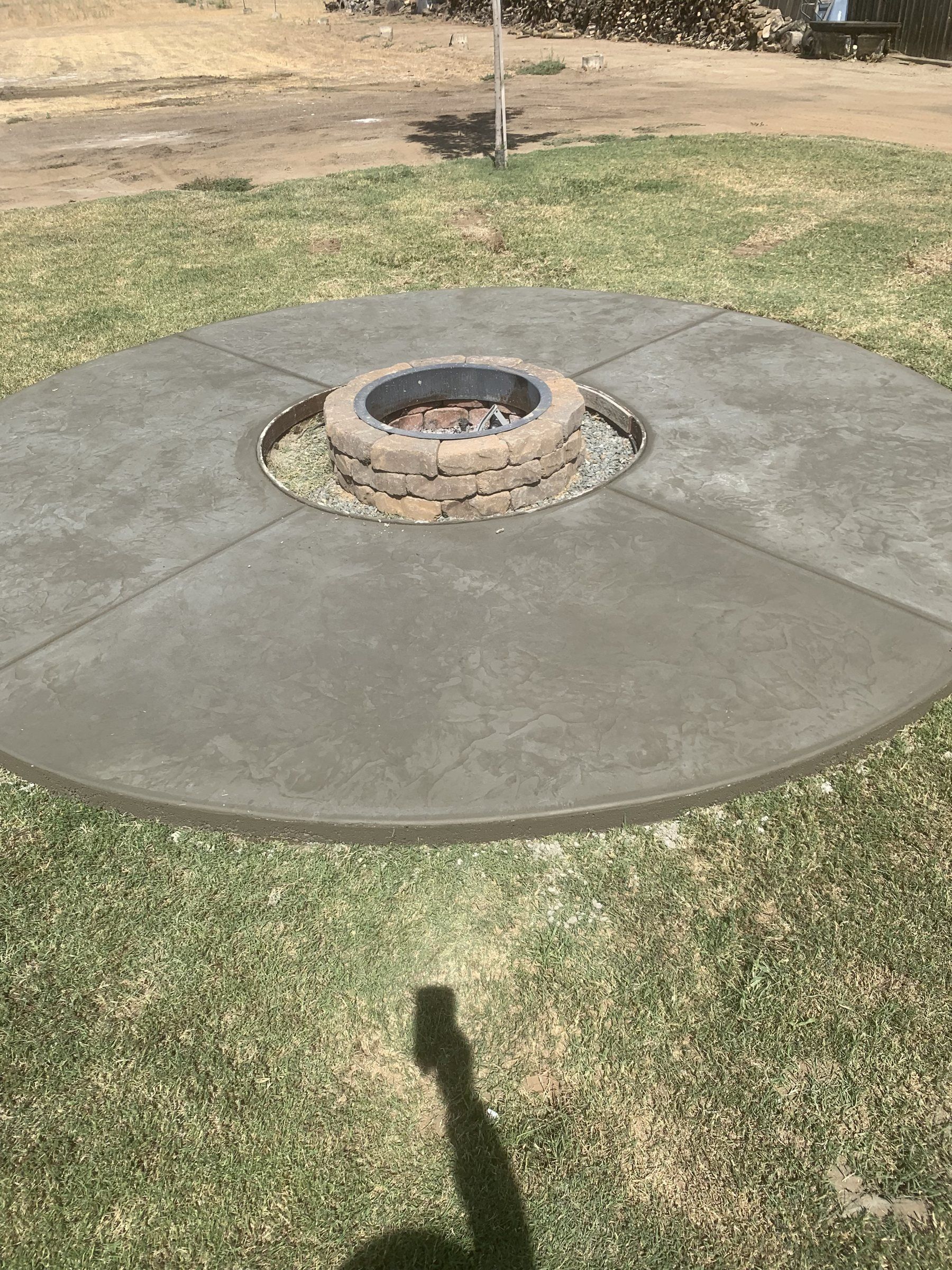 Round stamped concrete patio built around a stone fire pit