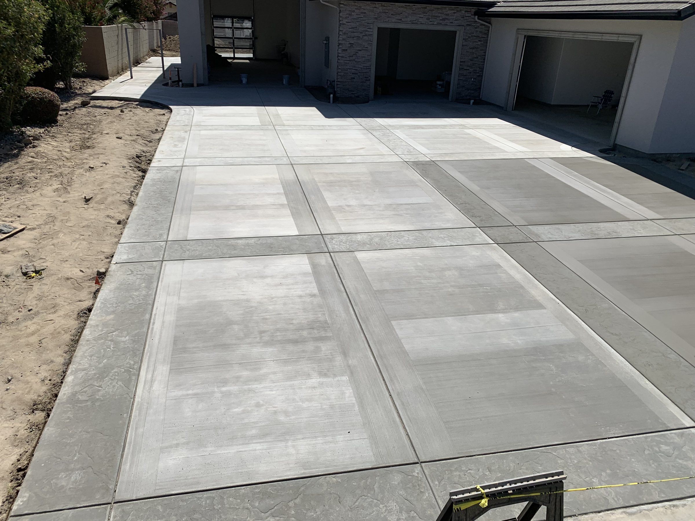 Long concrete driveway with smooth trowel bands framing broom-finish panels