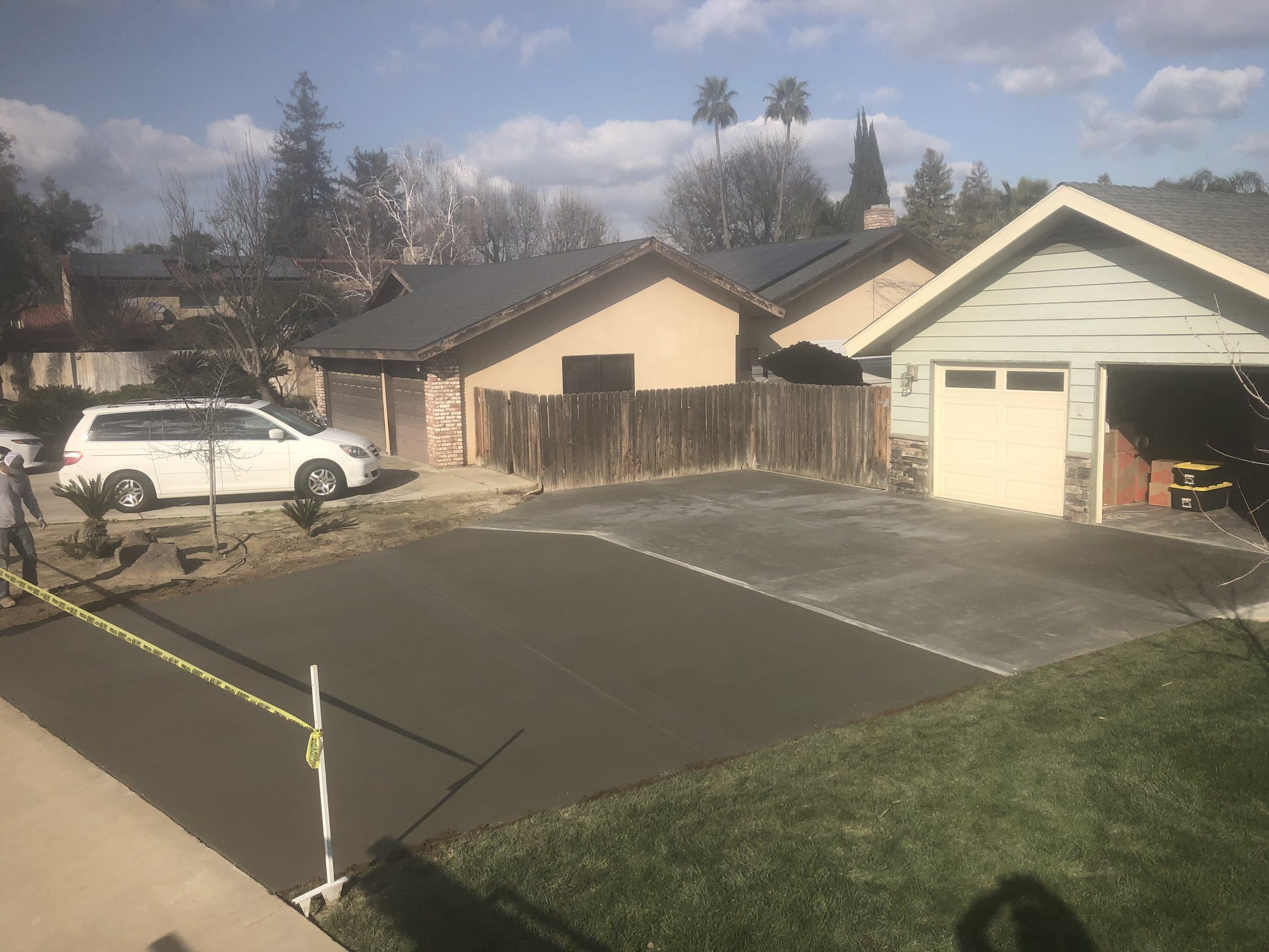 Wet concrete driveway with border bands curing in front of a house